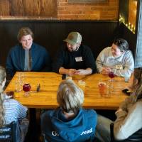 6 guests at event sitting at table and chatting
